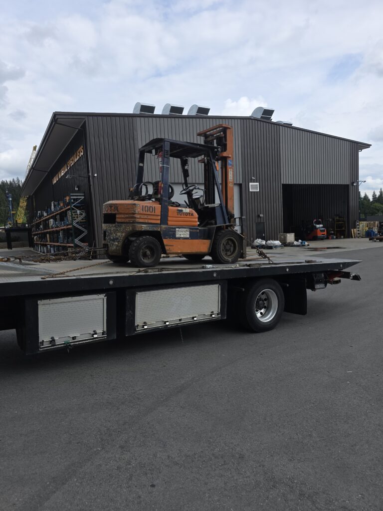 Old machinery pickup in North Vancouver - orange Toyota forklift loaded for transport